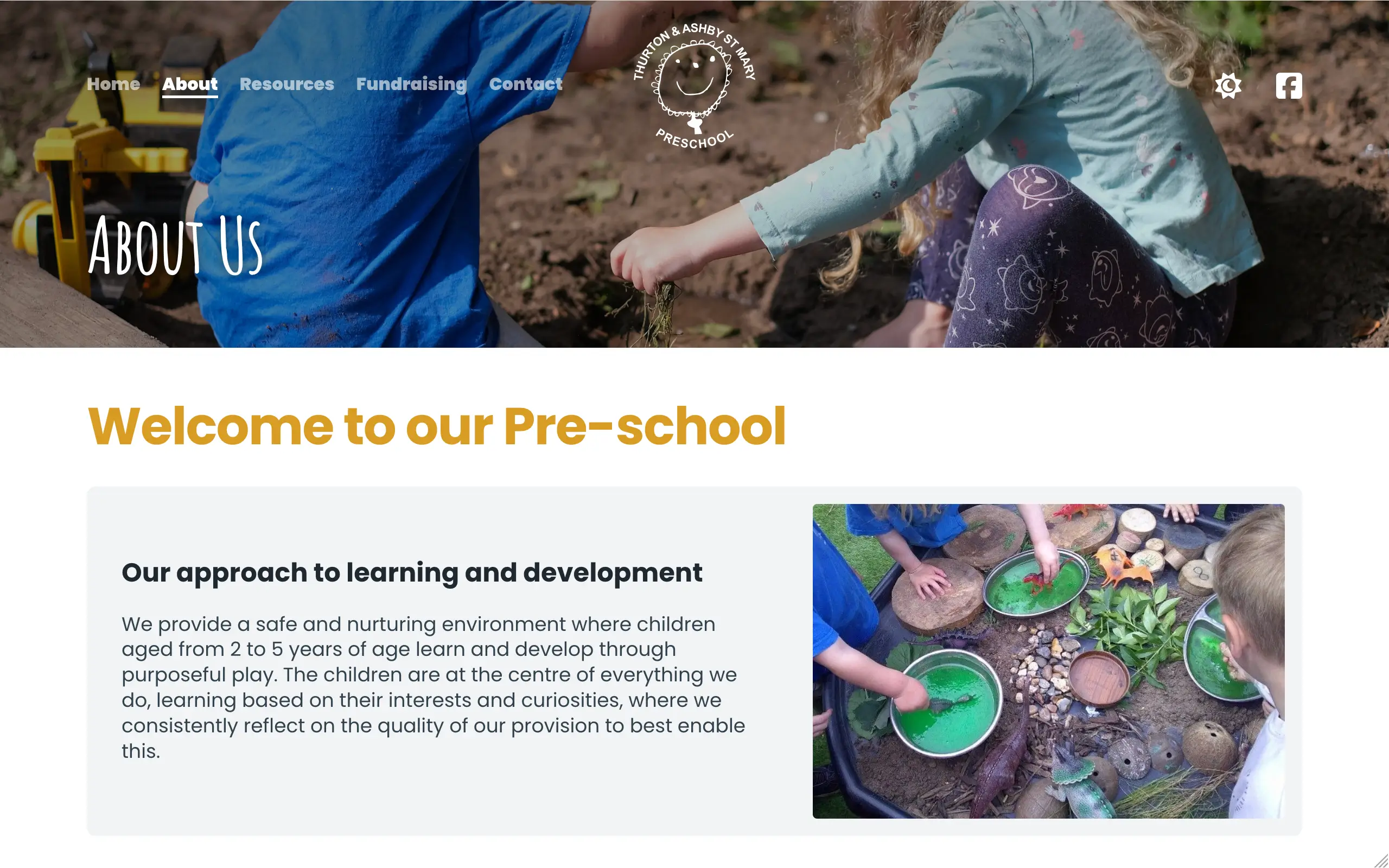 A screenshot of a preschool website's "About Us" page, with a wide banner image at the top showing two young children playing in soil outdoors, one in a blue T-shirt and the other in a sage green top with a printed leggings design. The preschool's circular logo, featuring a smiling face illustration, sits in the top right of the banner. Below, a welcome section includes a heading reading "Welcome to our Pre-school" and descriptive text about the setting's approach to learning, alongside a photograph of several children's hands engaged in a sensory play activity involving green liquid in metal trays, wooden discs, and small toy animals.